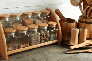 a group of glass jars with different spices on a wooden shelf