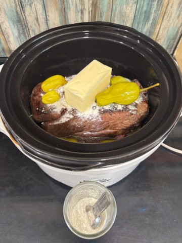 a slow cooker with a piece of meat and a piece of butter